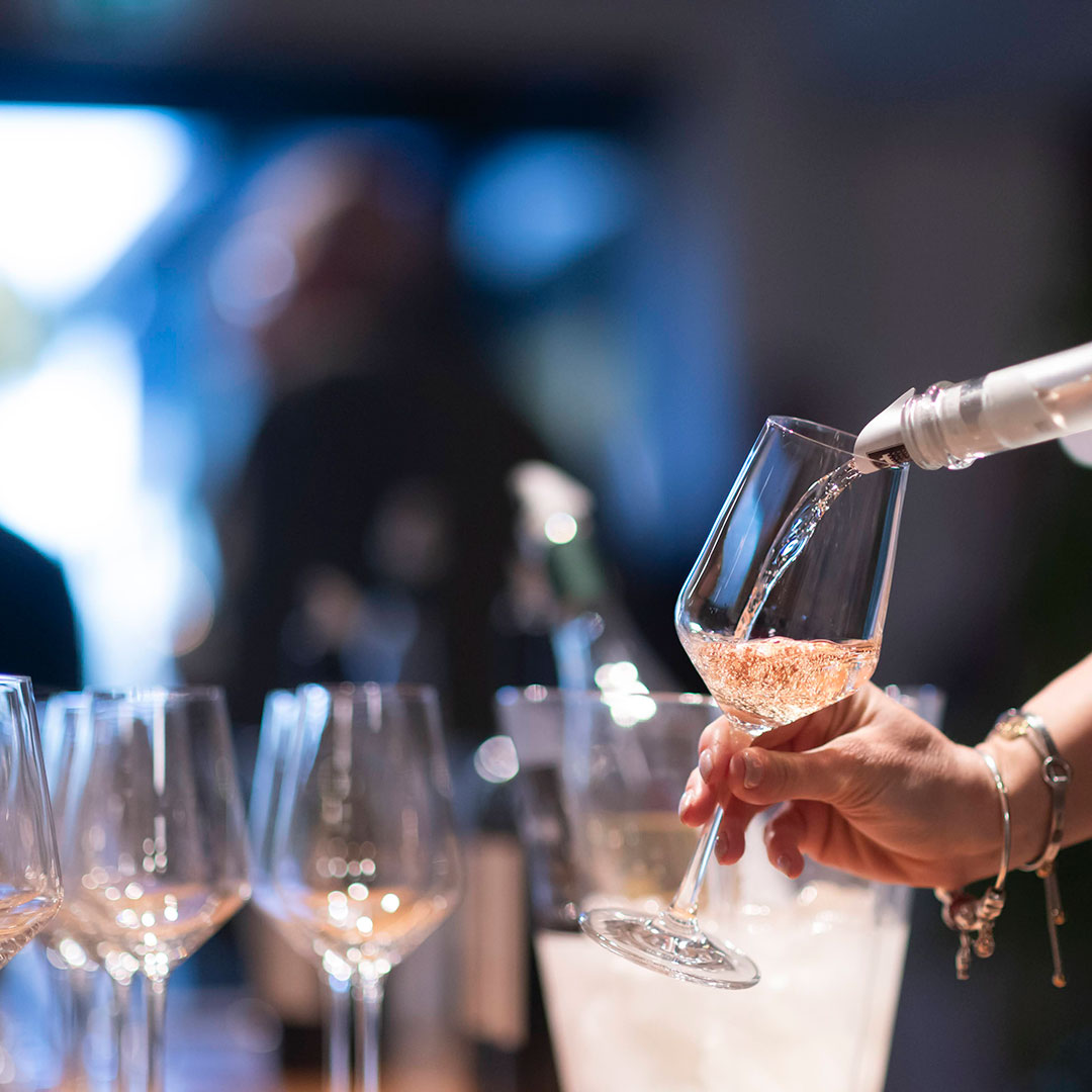 AMA_0913 mano che tiene un bicchiere in cui si sta versando del vino rosato